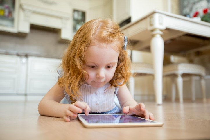 Concentrated little girl using touchpad on floor